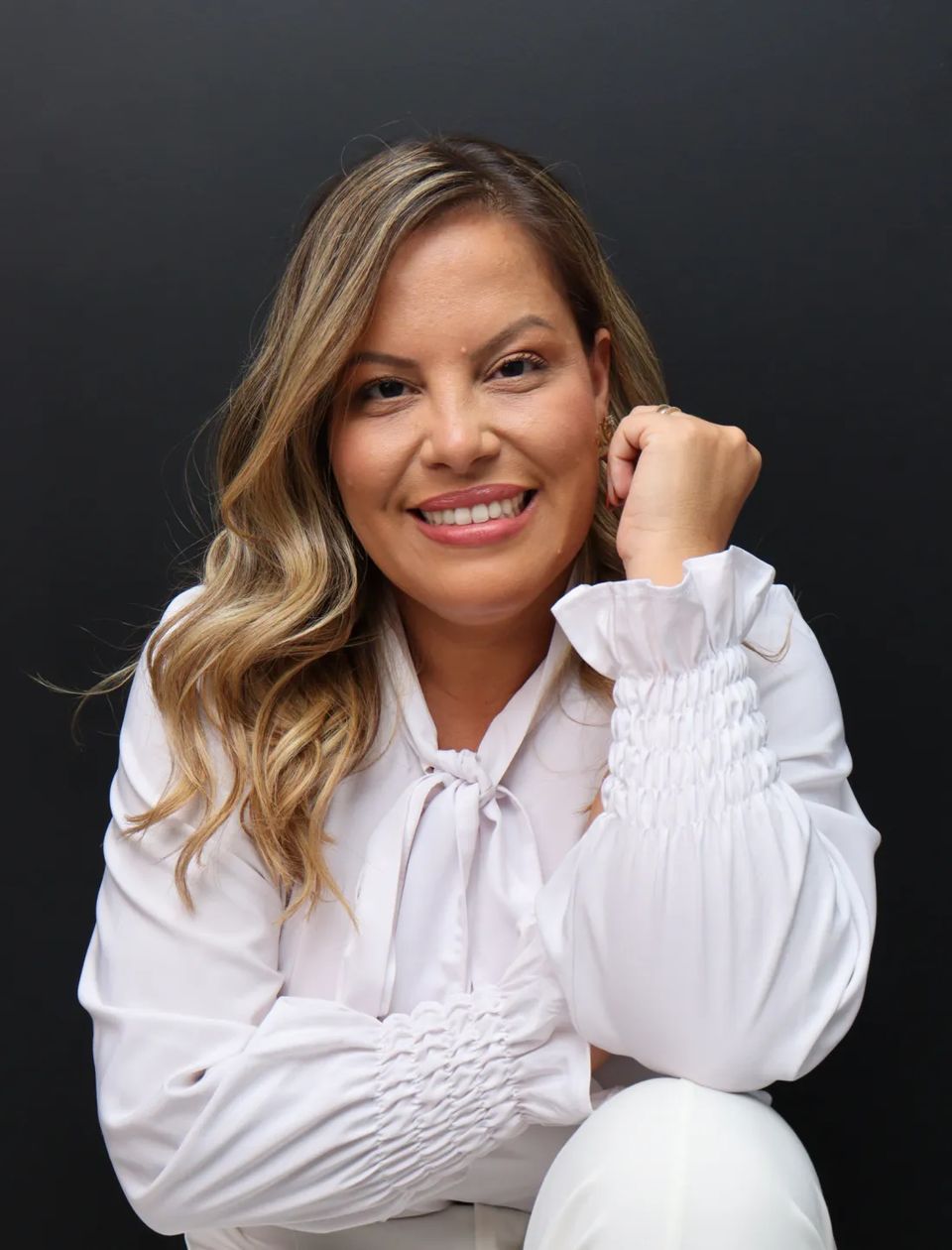 Carol Lorena, psicanalista, sorrindo, de blusa branca